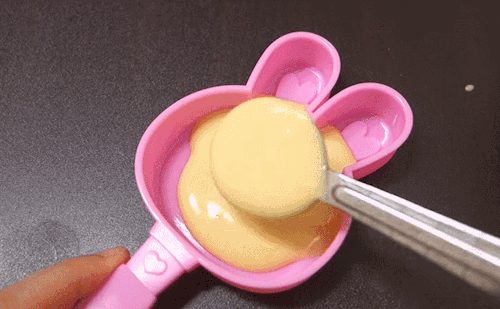 A peach-colored food mixture being placed into a bunny-shaped mold
